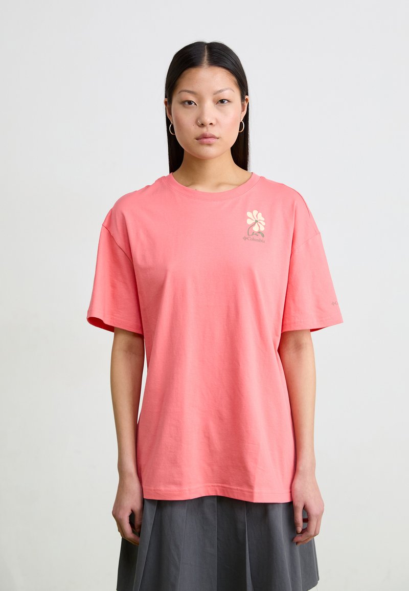 Koraalroze t-shirt met korte mouwen en een ontspannen fit. Kenmerkt zich door een bloemenlogo in lichtbeige op de borst. Zacht katoenen materiaal.