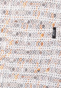 Patroonstof met geometrische ontwerpen in oranje, grijs en wit. Inclusief een patch pocket en een zwart merklabel.