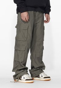 Cargo byxor i olivgrön färg, med flera sidofickor, en avslappnad passform och åtdragna anklar. Matchas med flerdelade sneakers.