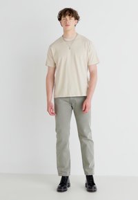 Beige puuvillane t-särk, mis on paaritatud helesiniste pükstega. Mustad nööriga saapad täiustavad välimust. Lihtne disain, lühikesed varrukad ja sirge lõige.