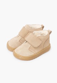 Botines de ante beige con una correa de velcro, forro suave y suela de goma. Punta redondeada y construcción resistente diseñada para la comodidad.