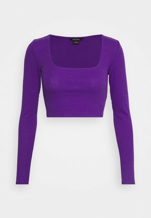 Lila geripptes Crop-Top mit langen Ärmeln und quadratischem Ausschnitt. Der Stoff ist glatt und hat eine figurnahe Silhouette, die ein einfaches Design betont.