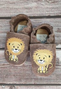 Bruine stoffen slippers met een gerimpelde rand, voorzien van een geborduurde leeuw met een gouden manen en poten. Zachte textuur en flexibel ontwerp.