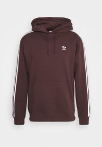 Sudadera color marrón oscuro hecha de una mezcla de algodón, con un bolsillo frontal, capucha con cordón y rayas laterales blancas. Pequeño logo blanco en el pecho.