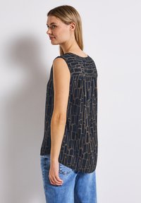 Ärmlös topp i mörkblått tyg med ett geometriskt mönster i ljusbrunt. Har en rund halsringning och plisserad detalj bak.