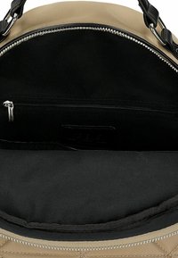 Sac à main matelassé beige avec un intérieur noir. Doté d'une fermeture éclair en métal argenté et d'une poche intérieure avec fermeture éclair. Texture lisse et poignées robustes.