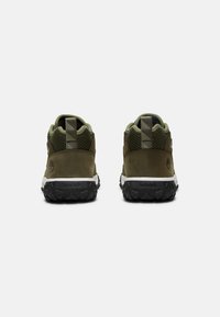 Brązowe i oliwkowo-zielone buty trekkingowe z siateczkowym wierzchem, czarną gumową podeszwą oraz uchwytem z tyłu. Wytłoczone logo Timberland po boku.