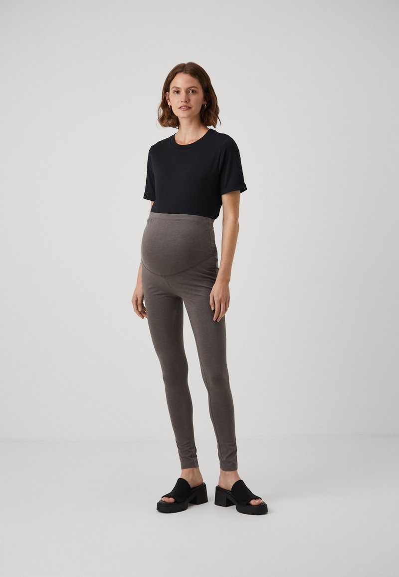 Leggings de maternidade em mistura de algodão cinza com um cós alto e elástico. Combinados com uma blusa justa de manga curta preta e sandálias plataforma pretas.