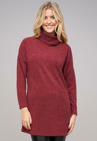 Garās piedurknes turtlenecks tunika izgatavota no teksturētas bordo auduma, piedāvājot brīvu piegriezumu un vienkrāsainu dizainu bez rakstiem vai rotājumiem.