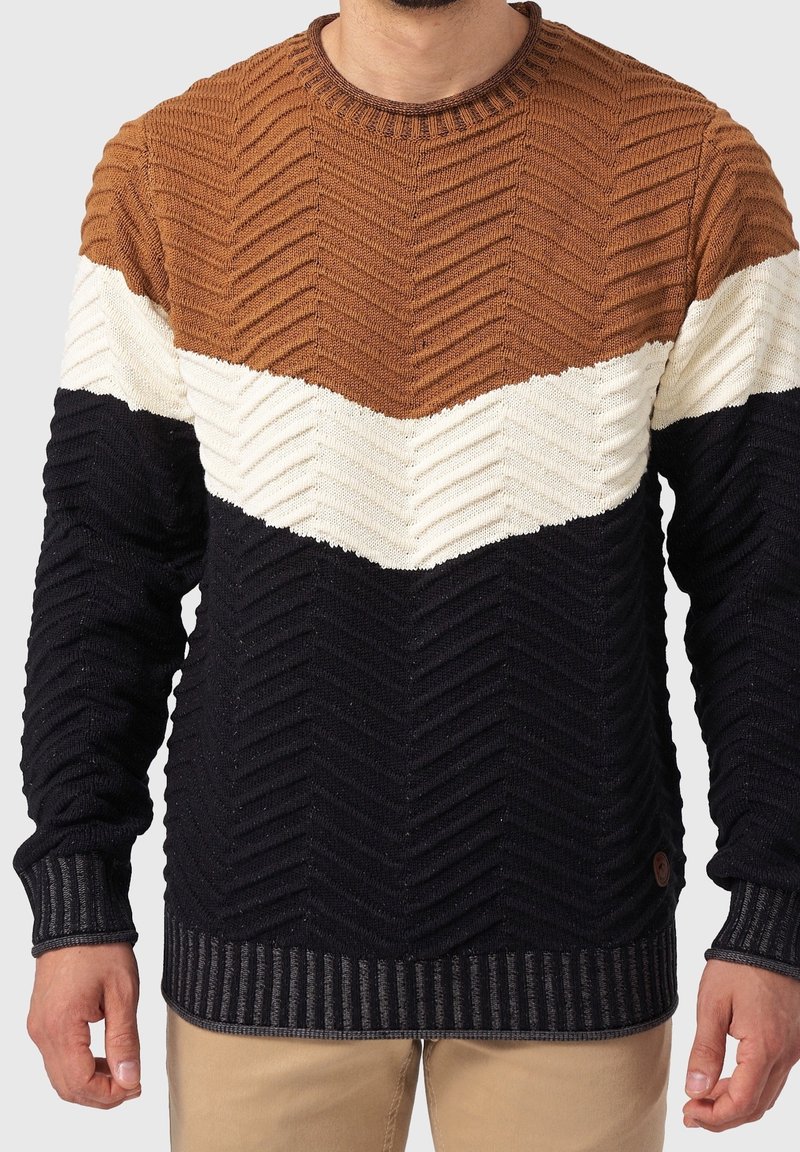 Pull en tricot avec un motif chevron en marron, crème et marine. Encolure ronde, poignets et ourlet côtelés ; finition texturée. Détail du logo présent.