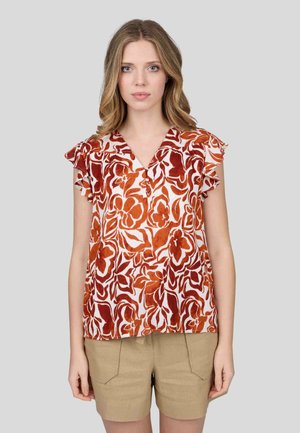 Blouse florale orange et blanche, avec un décolleté en V et des manches à volants. Tissu léger avec une coupe ample, associée à un short beige.