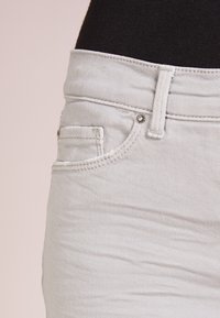 Ljust grå denimjeans med en slim passform, med en liten framficka, förstärkt sömnad och en metallknapp i midjan.