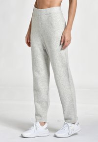 Ljust grå, höga sweatpants i mjukt tyg med en texturerad yta, som har en avslappnad passform och sidofickor. Matchas med vita sneakers.