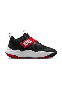 Baskets de sport noires avec accents rouges, dotées d'un dessus texturé, d'une large semelle intermédiaire et d'une sangle proéminente avec le logo "Nike".