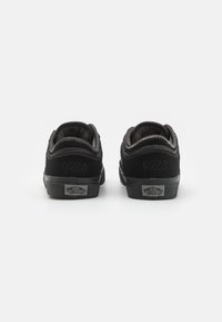 Sneaker nere in suede con talloni arrotondati, cuciture grigie e suole in gomma. Presentano etichette con il logo e il numero “66/99” impresso sui talloni.