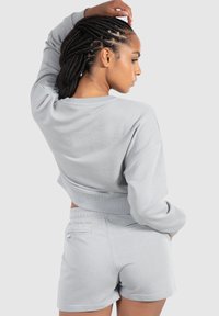 Lys grå cropped sweatshirt med ribstrikkede manchetter, parret med matchende shorts der har sidelommer og en blød bomuldsstruktur.