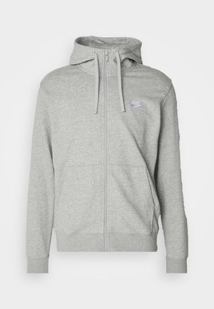 Sudadera gris con cremallera, con un bolsillo tipo canguro, capucha ajustable y un pequeño logo de Nike en púrpura en el pecho. Fabricada con un tejido suave y texturizado.