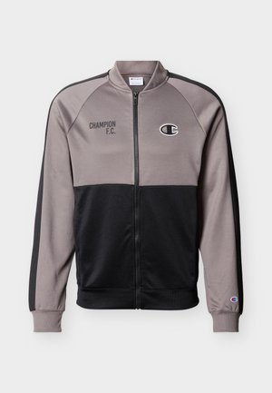 Δίχρωμο μαύρο και γκρι μπουφάν με φερμουάρ, με το κείμενο "CHAMPION F.C." και το λογότυπο της Champion στο στήθος, καθώς και λογότυπο στην μανσέτα του αριστερού μανικιού.