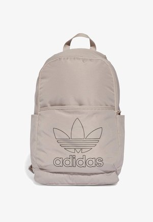 Sac à dos beige Adidas avec poche zippée à l'avant et logo trefoil Adidas noir ainsi que texte sur le devant, avec une poignée de transport supérieure.