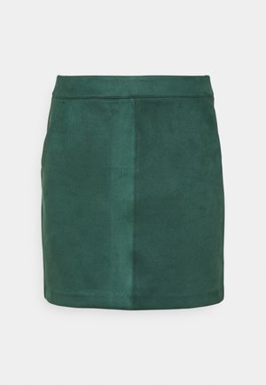 Mini-jupe en daim vert à la texture lisse, coupe droite et lignes épurées. Elle comporte des poches latérales invisibles et une ceinture.