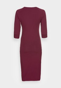 Burgundy midiklänning med 3/4 raglanärmar. Tillverkad av mjukt tyg, har en rundad halsringning och sidslitsar i fållen.