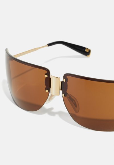 Lunettes de soleil marron au design audacieux et angulaire. Accents en métal doré au niveau des charnières. Branches noires. Fini lisse et brillant.