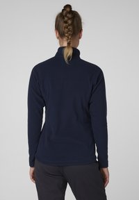 Granatowa polarowa kurtka z wysokim kołnierzem i długimi rękawami. Gładka tekstura, dopasowany krój, widoczne szwy wzdłuż szwów.