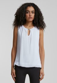 White sleeveless blouse with a keyhole neckline, soft fabric, and a slight sheen. Features small decorative accents at the neckline.