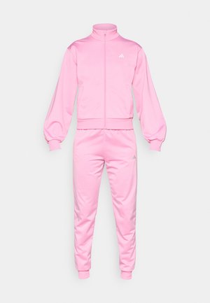 Simogató poliészterből készült rózsaszín tréningruha, magas gallérral, elöl zipzárral és elasztikus mandzsettákkal az ujjakon és a bokákon, logó díszítéssel.