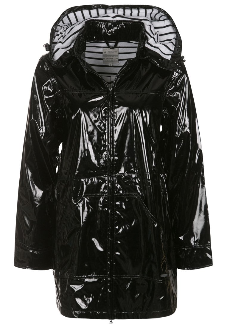 Musta, kiiltävä, vedenpitävä takki vetoketjulla, kahdella etutaskulla ja raidallisella hupun vuorauksella. Takissa on löysä istuvuus ja puolipitkä malli.