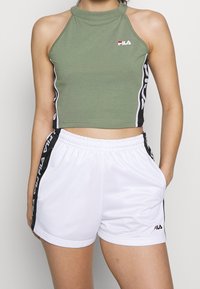 Olive green cropped halter top featuring white side stripes; white shorts with black side accents and logo. Both are made of soft fabric.