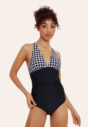 Maillot de bain une pièce avec un haut à carreaux noir et blanc et un bas noir uni, doté d'un décolleté plongeant et de bretelles réglables.