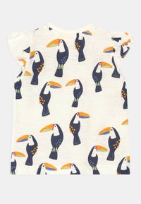 T-shirt branca de manga curta com um padrão repetido de tucanos coloridos com bicos laranja e corpos azul-marinho, detalhe de ombreira franzida.