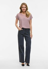 T-shirt rose clair à manches courtes associé à un jean large taille haute en denim foncé et des escarpins noirs à bout pointu. Tenue simple et décontractée.