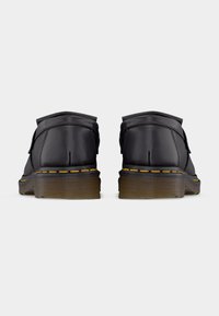 Crne kožne gležnjače zaobljenog vrha, s žutim šavovima uz potplat i teksturiranim smeđim gumenim đonom.