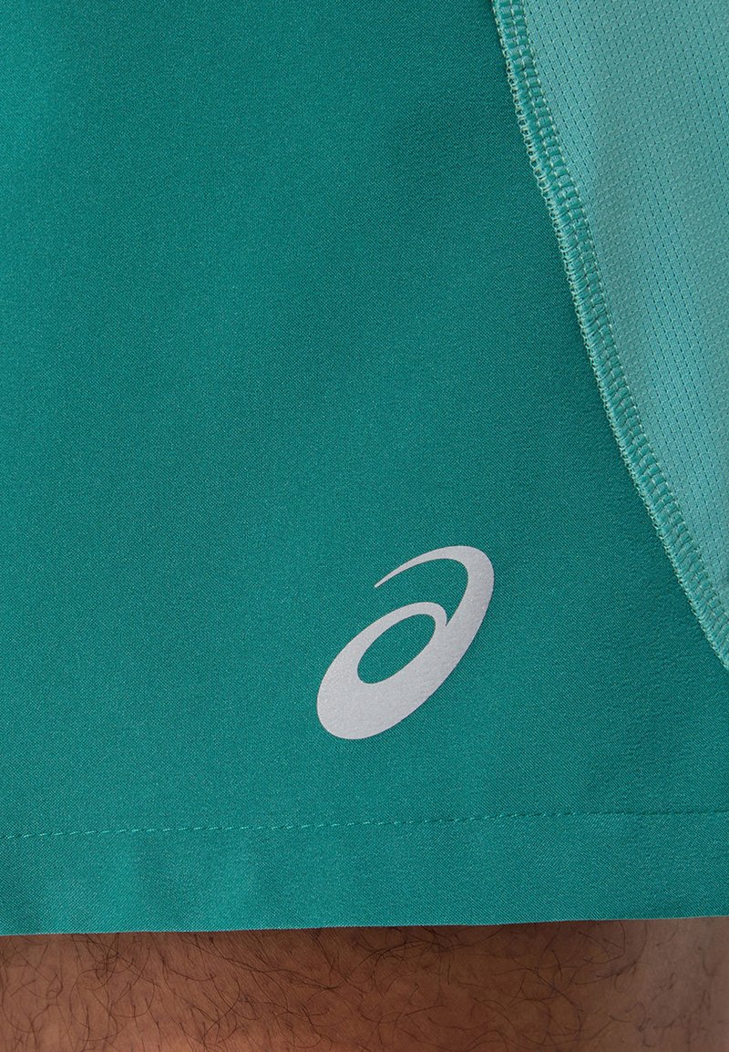 Teal sportshorts van gladde stof, met een iets gestructureerd zijpaneel, voorzien van een zilveren logo op de linkeronderkant.