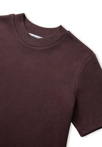Camiseta de manga corta y cuello redondo en algodón de color burdeos oscuro. Textura suave con costuras visibles en las mangas y el dobladillo.