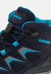 Dunkelblaue Wanderschuhe mit türkisfarbenen Akzenten, strukturiertem Obermaterial, gepolstertem Schaft und Schnellzugsystem. Enthält ein graues synthetisches Designelement.