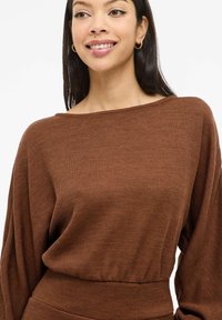 Brązowy prążkowany sweter z szerokim dekoltem w łódkę i długimi, luźnymi rękawami. Posiada marszczoną talię dla dopasowanego kroju.