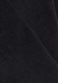 Tela negra texturizada con una superficie suave, que presenta una ligera elasticidad y un sutil brillo, dispuesta en pliegues.