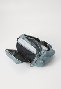 Light blue backpack with adjustable straps, multiple zippered compartments, and a textured black interior. Front pocket features a mesh lining.