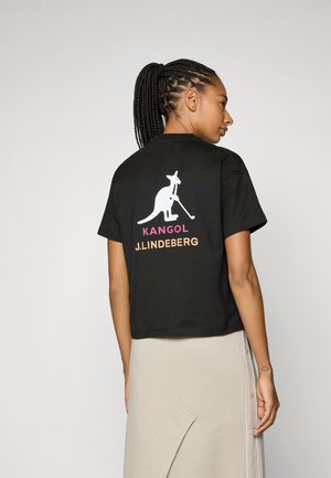 Black cropped t-shirt featuring a white kangaroo graphic and "KANGOL" in pink and "J.LINDEBERG" in orange on the back. Soft fabric.
