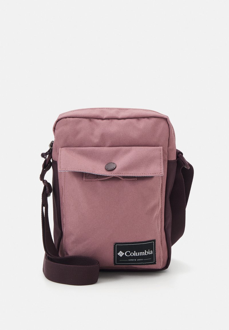 Borsa a tracolla rosa in tessuto con chiusura a pattina, tasca frontale, tracolla regolabile e patch logo nero. Texture liscia con cuciture resistenti.