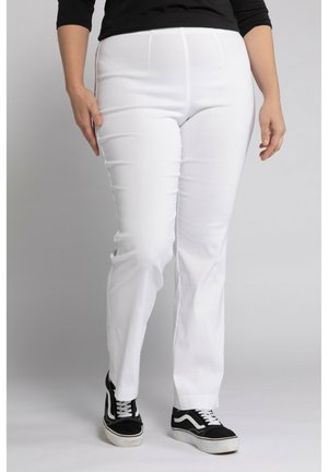 Bílé slim-fit kalhoty vyrobené z elastické látky, s hladkou texturou a minimálním zdobením, spárované s černými teniskami.