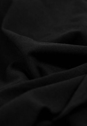 Tissu noir avec une texture douce et lisse, présentant des plis et des rides visibles, indiquant une composition matérielle légère et flexible.