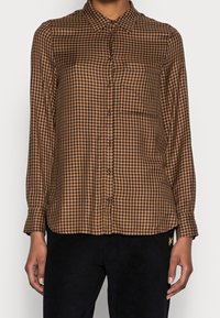 Camicia a maniche lunghe a quadri marrone e nera con colletto button-down, bottoni anteriori e una tasca sul petto. Tessuto leggero, morbida texture.