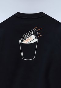 Ψηφιακό ρολόι ξυπνητήρι που εμφανίζει τη λέξη "ΚΟΥΡΑΣΜΕΝΟΣ" με κουμπί "ΑΝΑΒΟΛΗ", πέφτοντας σε κάδο απορριμμάτων στην πλάτη ενός μαύρου ρούχου.