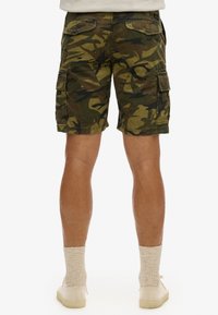 Shorts cargo en un patrón de camuflaje que presenta tonos de verde y marrón. Incluye dos bolsillos laterales y dos bolsillos traseros con solapa. Material de algodón.