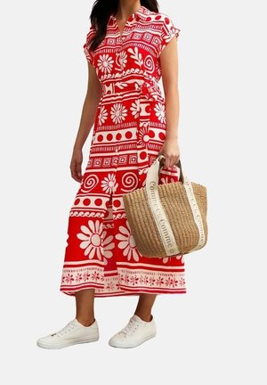 Nainen pukeutuneena puna- ja valkokuviolliseen puolipitkään mekkoon, jossa on lyhyet hihat, kantaa punottua ostoskassia ja käyttää valkoisia lenkkareita.