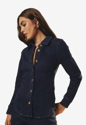 Dunkelblaues Denim-Jackett mit durchgehender Knopfleiste, spitzem Kragen, langen Ärmeln und dezenten Nähten.